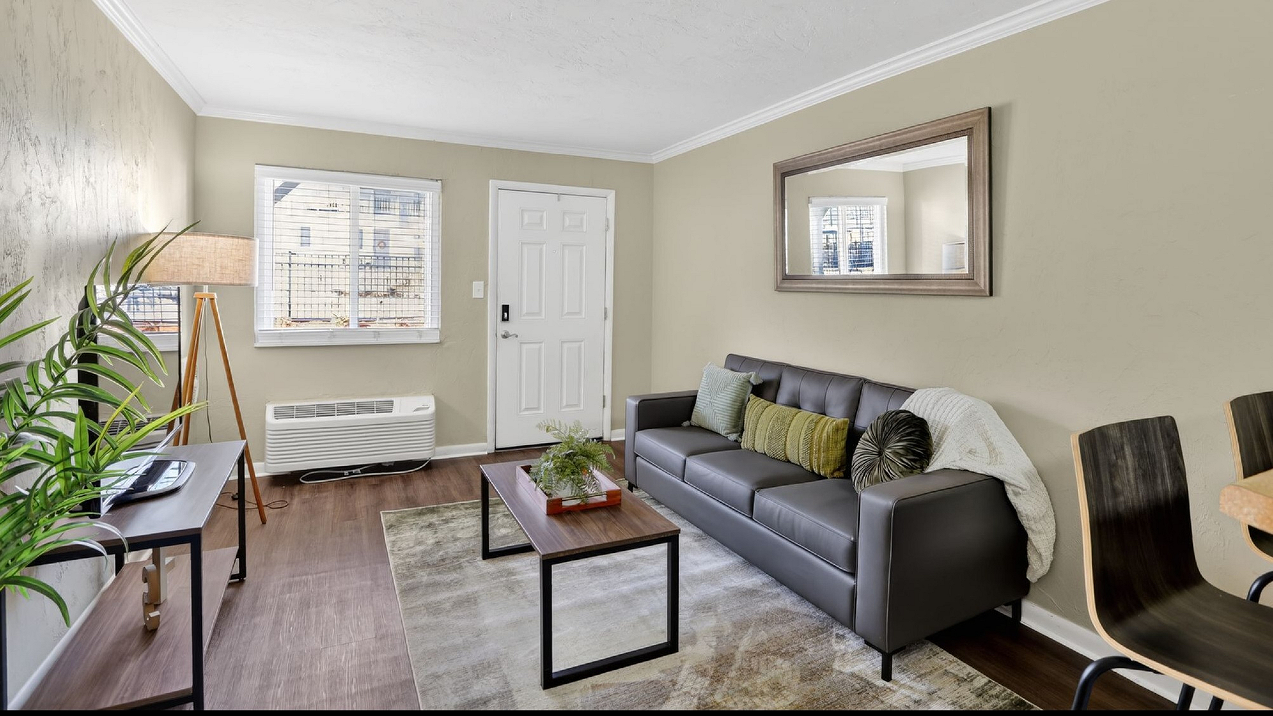 Bright and inviting living room featuring a sleek gray sofa with accent pillows, modern floor lamp, and stylish wooden coffee table, perfect for relaxation and comfort.