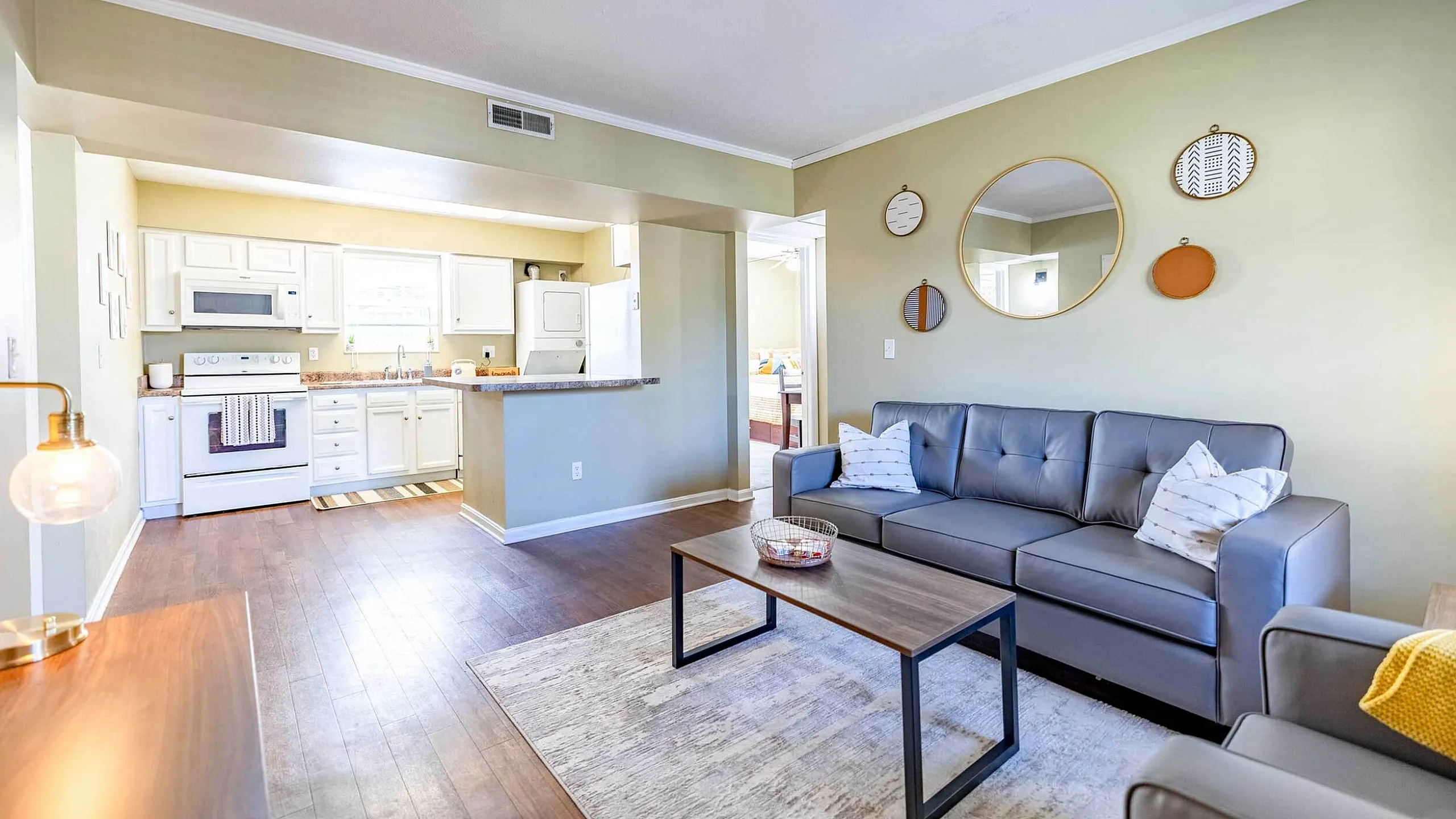 Bright and inviting open-concept living space with modern kitchen, cozy gray sofa, and chic decor accents.