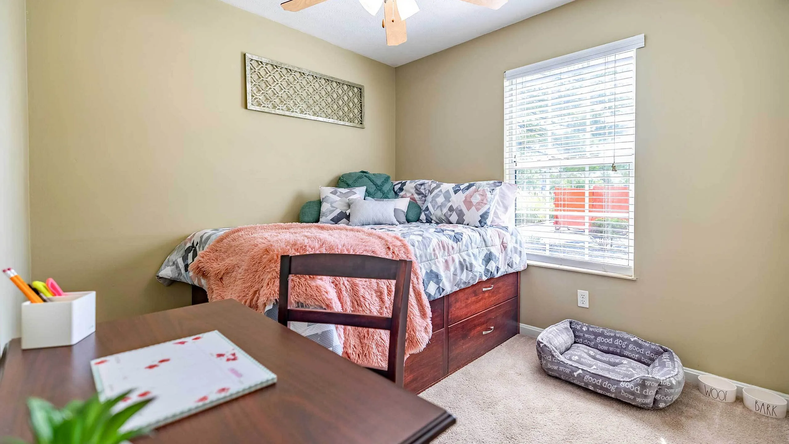 Inviting bedroom with natural light, cozy bedding, and a small desk, perfect for a comfortable and functional living space.