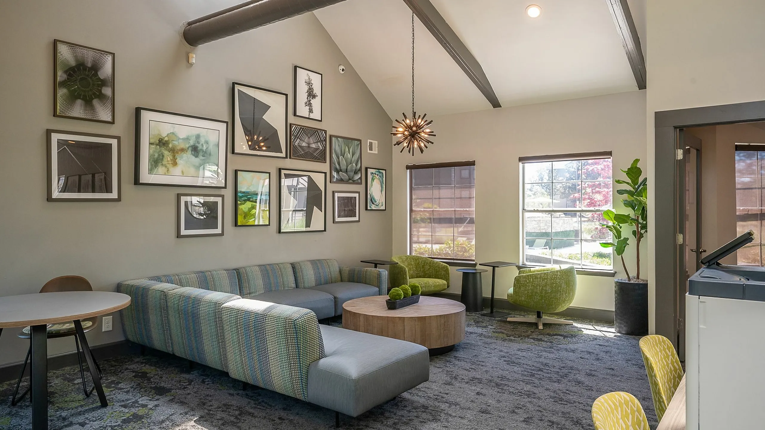 Inviting and modern common area with stylish decor, featuring a cozy sectional sofa, vibrant artwork, and abundant natural light.