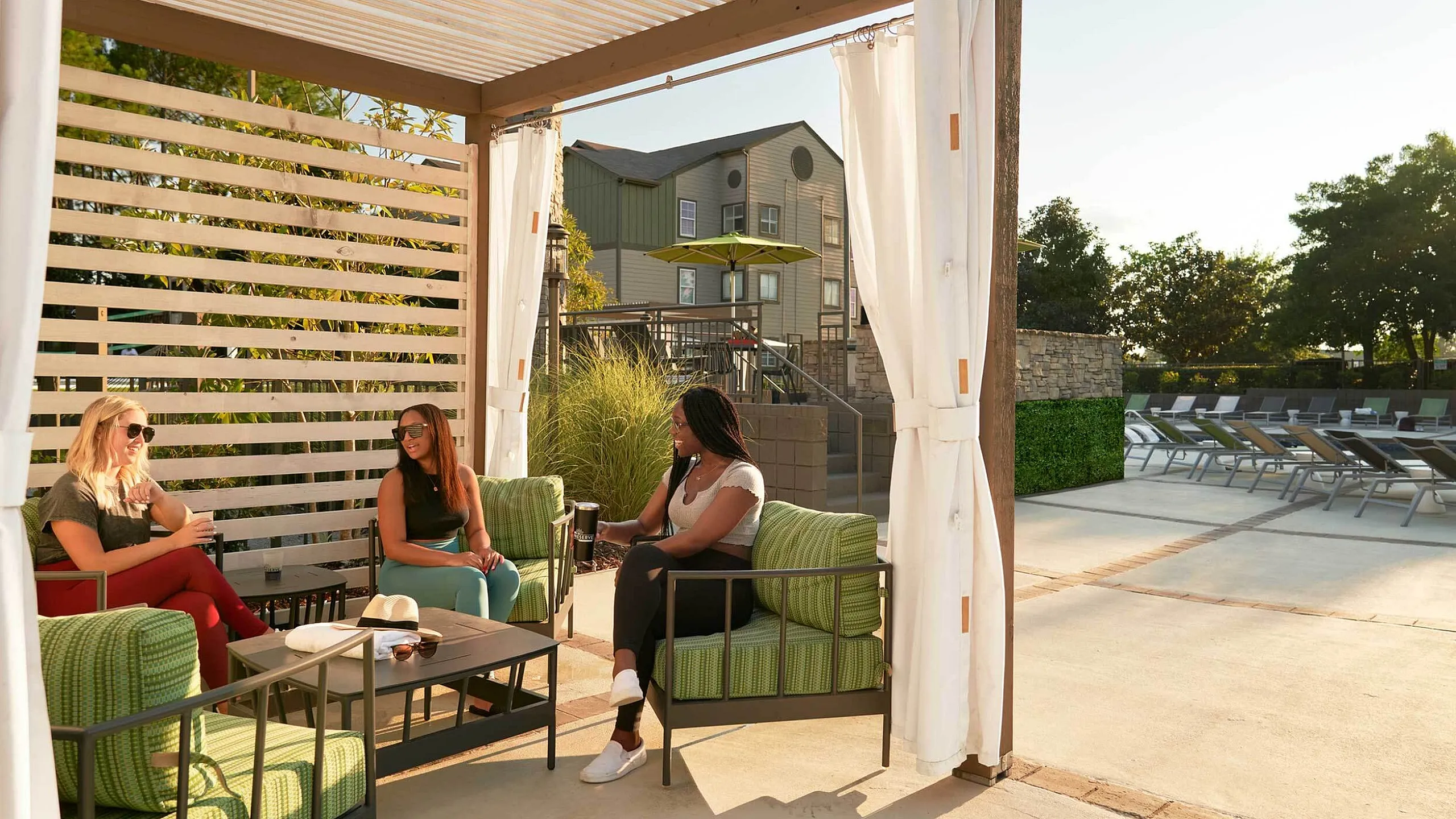 Chic outdoor lounge area featuring cozy seating beneath a stylish pergola, perfect for relaxation by the pool.