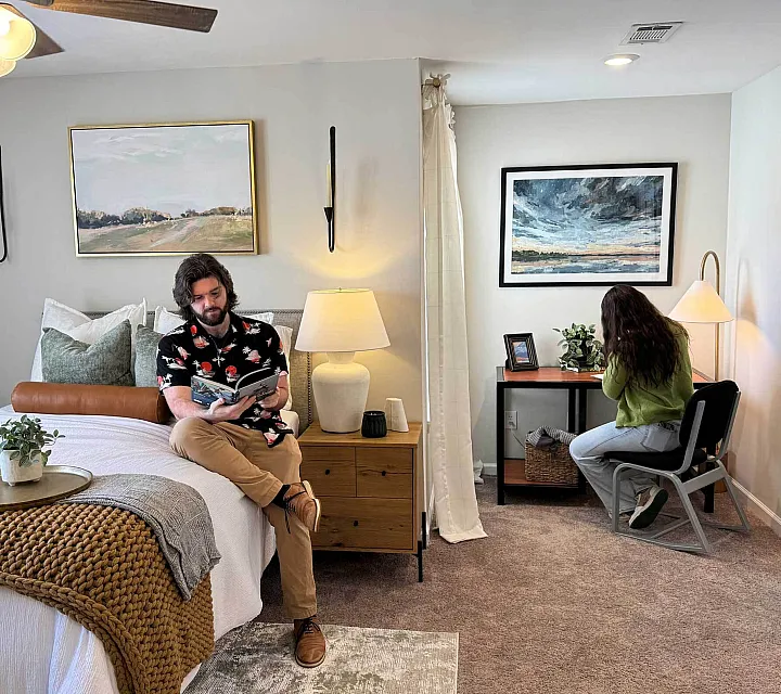 Cozy bedroom with stylish decor, featuring a plush bed, modern artwork, and a bright work nook perfect for relaxation and productivity.
