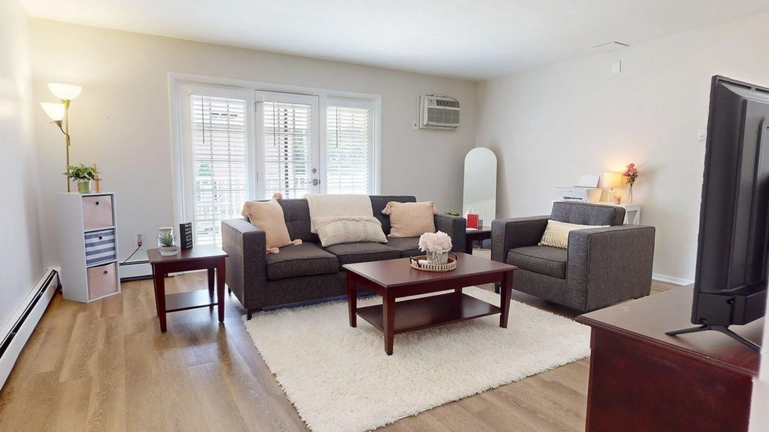 Inviting living room with stylish gray sofas, a cozy rug, and natural light streaming through large windows.
