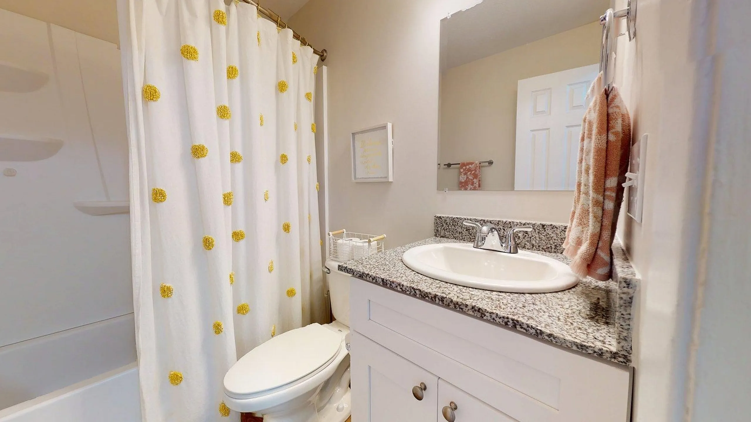 Charming bathroom with modern granite countertop, cozy decor, and a cheerful yellow polka dot shower curtain.