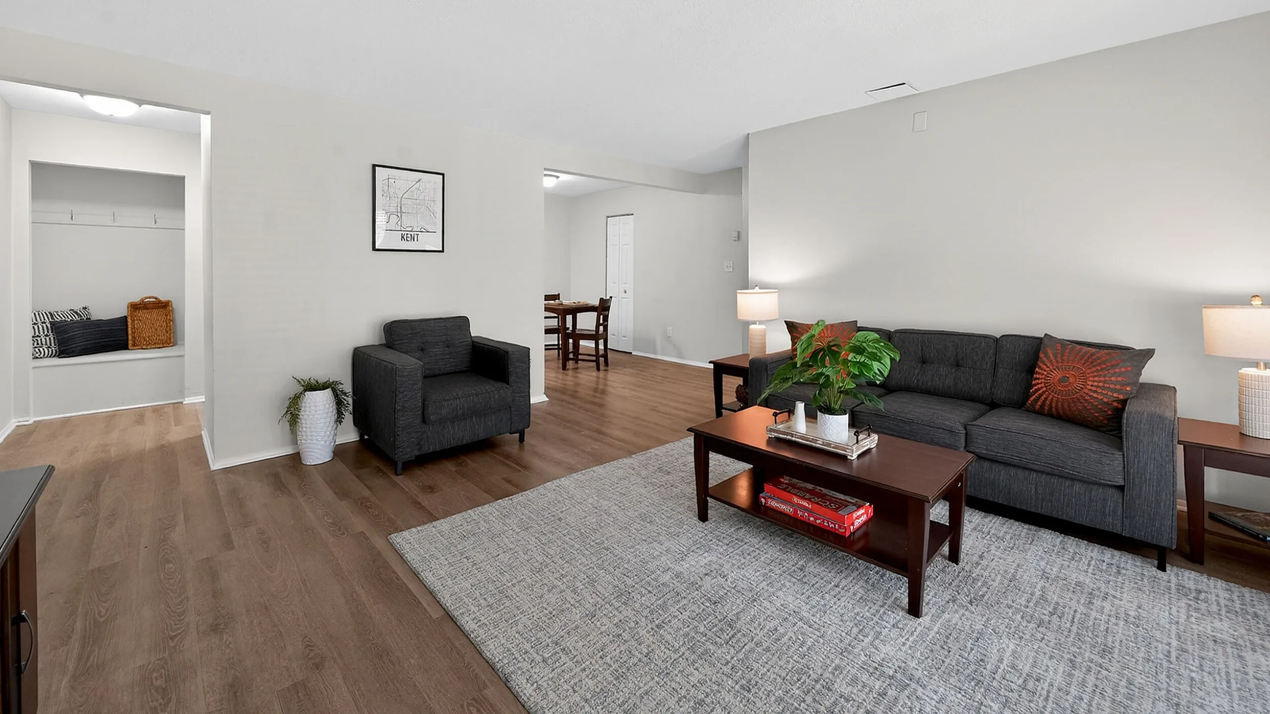 Modern living room with stylish decor, featuring a sleek gray sofa and armchair, accented by warm wooden flooring and soft lighting.