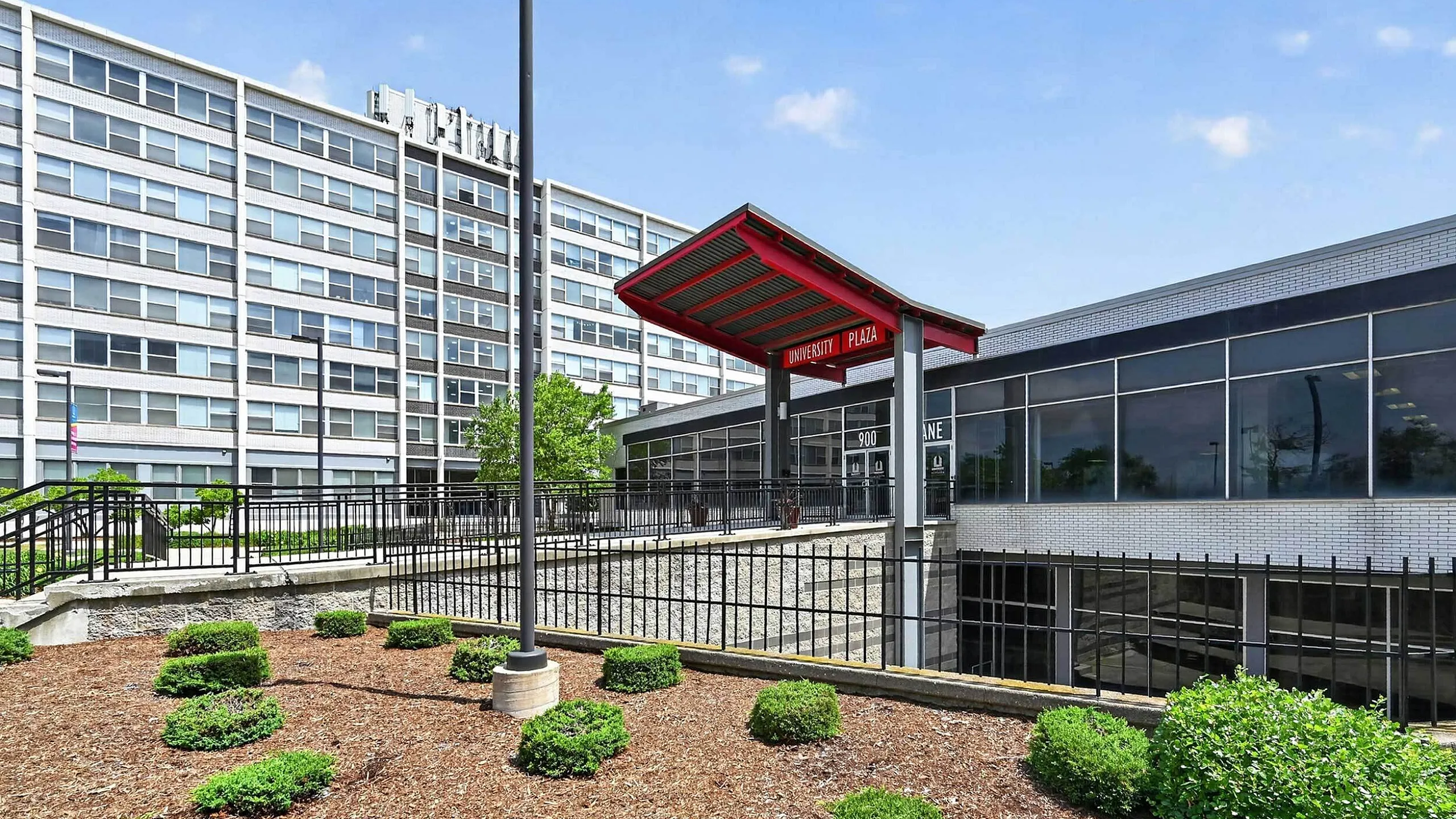 Modern university plaza entrance with sleek architecture and vibrant landscaping.