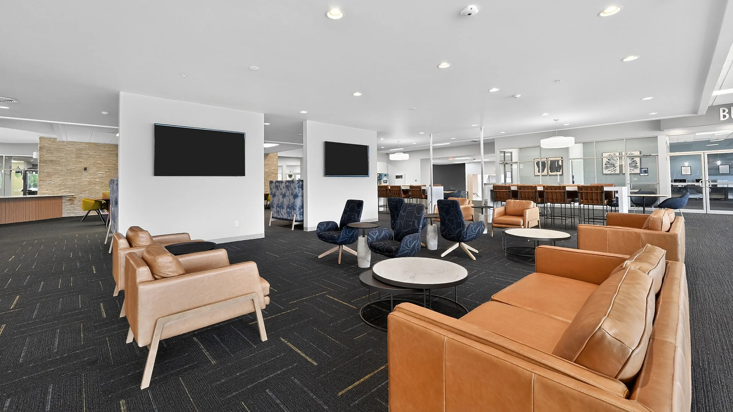 Spacious and modern lounge area featuring elegant leather seating, stylish coffee tables, and contemporary artwork in an inviting and well-lit environment.