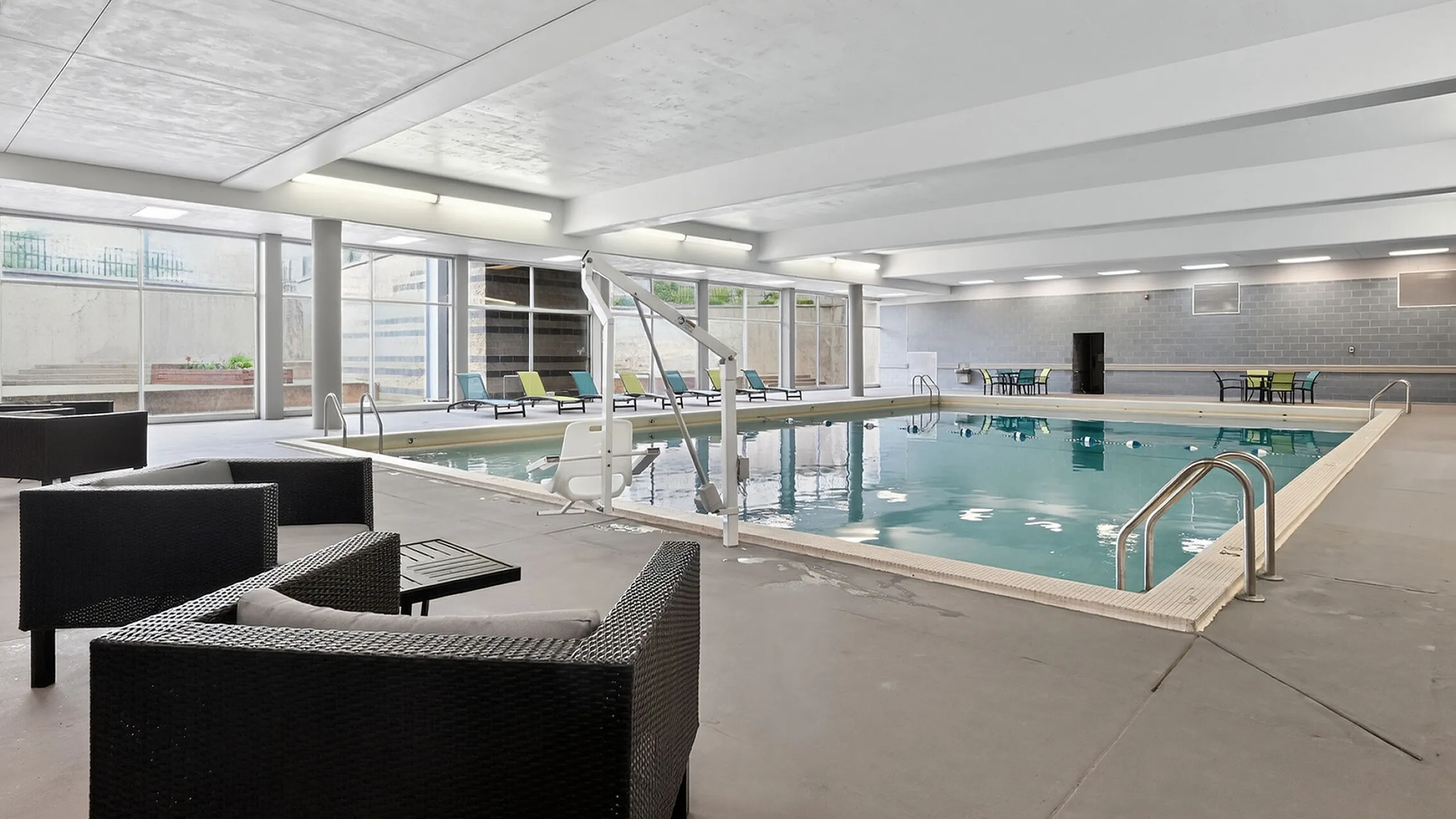 Luxurious indoor pool area with stylish seating and floor-to-ceiling windows for ample natural light.