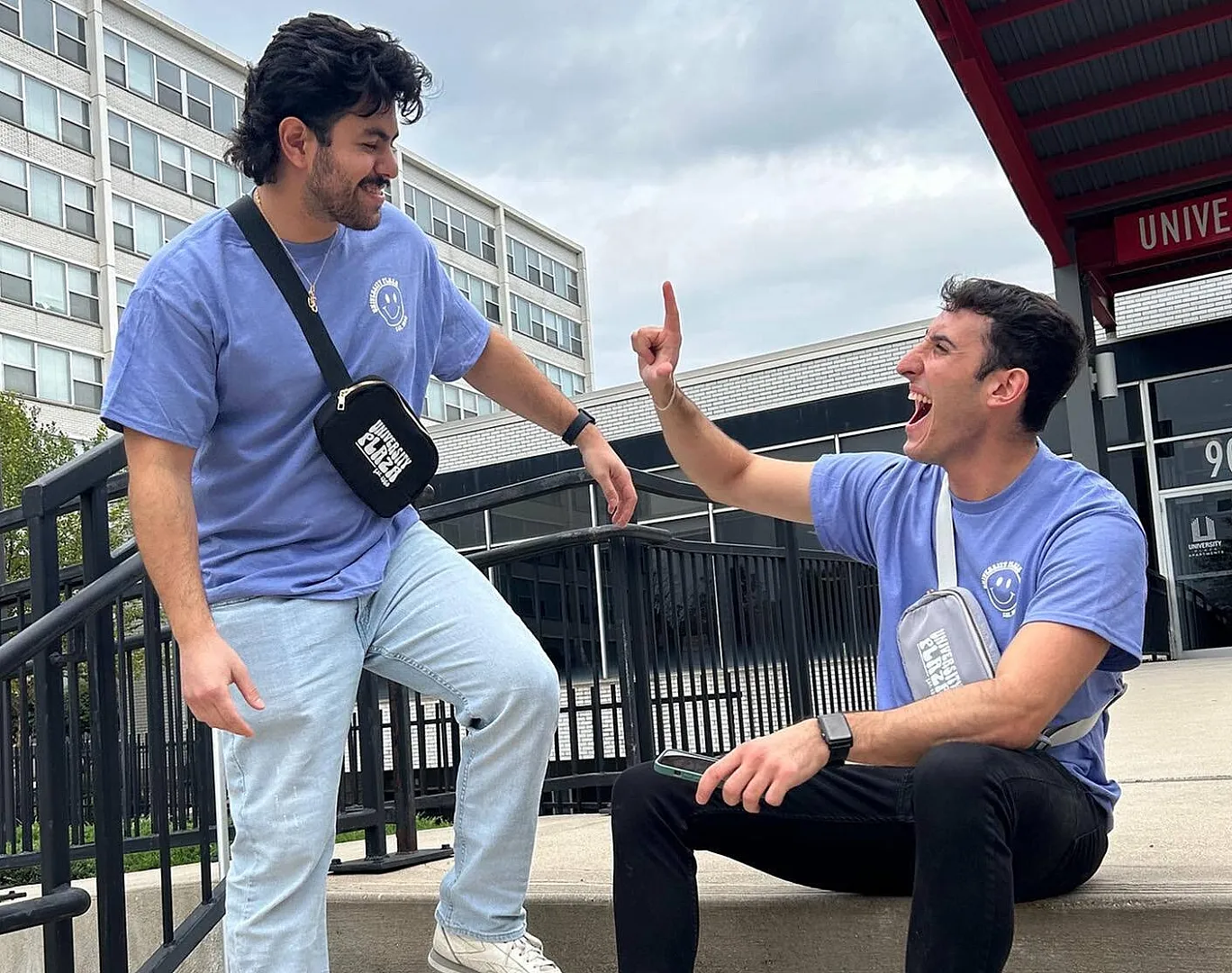 Two friends in casual outfits, sharing a joyful conversation on outdoor steps with a modern building backdrop.