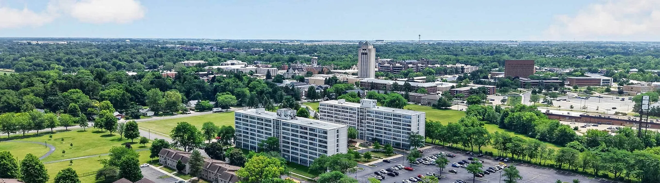 Stunning aerial view showcasing a vibrant community with lush green parks, modern apartment buildings, and scenic cityscape.