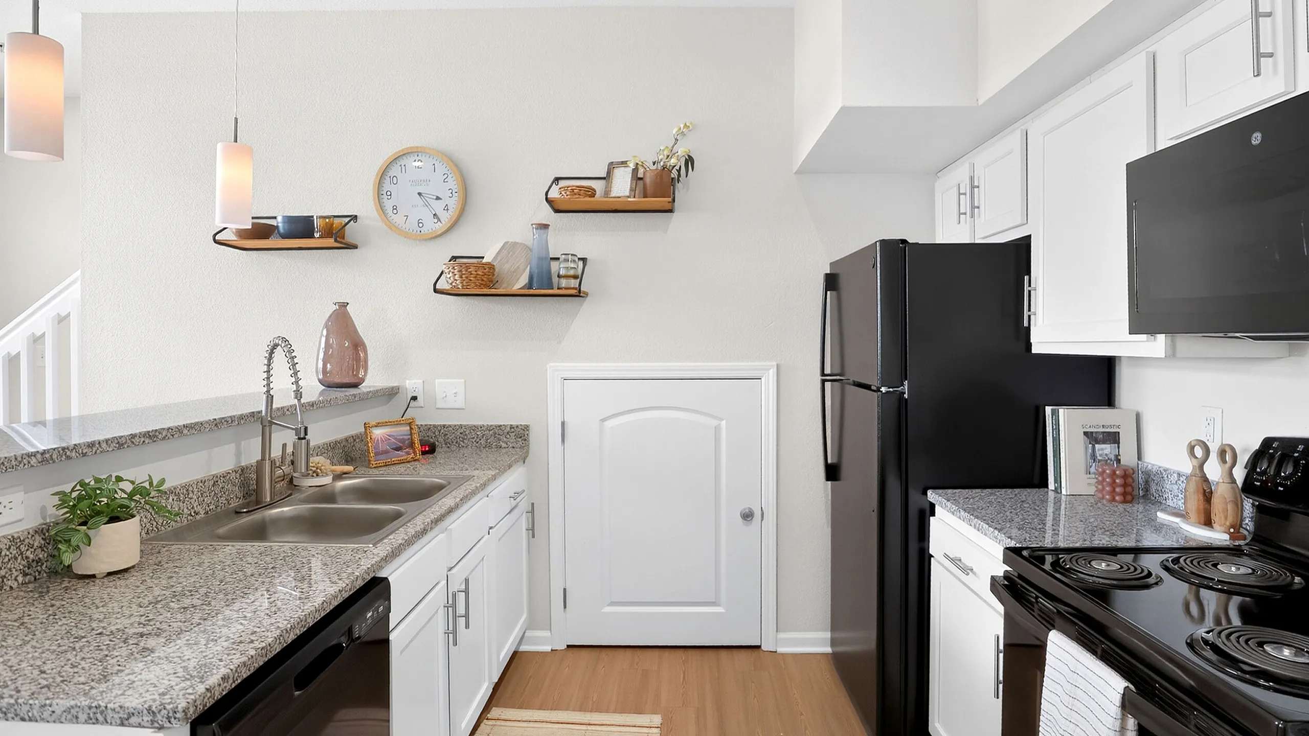 Modern kitchen with sleek granite countertops, elegant pendant lighting, and stylish open shelving adding contemporary charm.