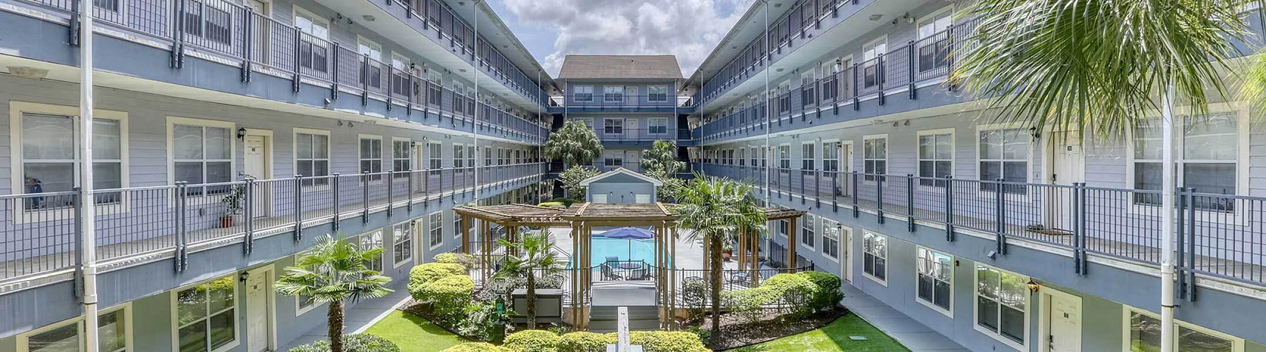 Bright, modern apartment complex with lush courtyard gardens and a central pool, perfect for urban living.