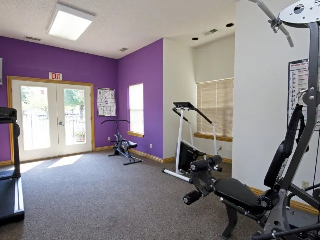 Bright fitness center with strength training equipment and colorful accent wall, located at Willow Creek Apartments in Springfield, MO.