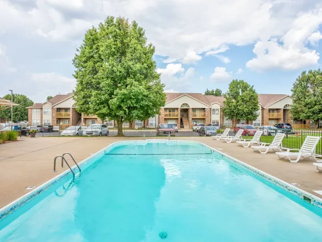 Resort-style swimming pool at Willow Creek Apartments with clear water and a view of the apartment buildings and surrounding trees.