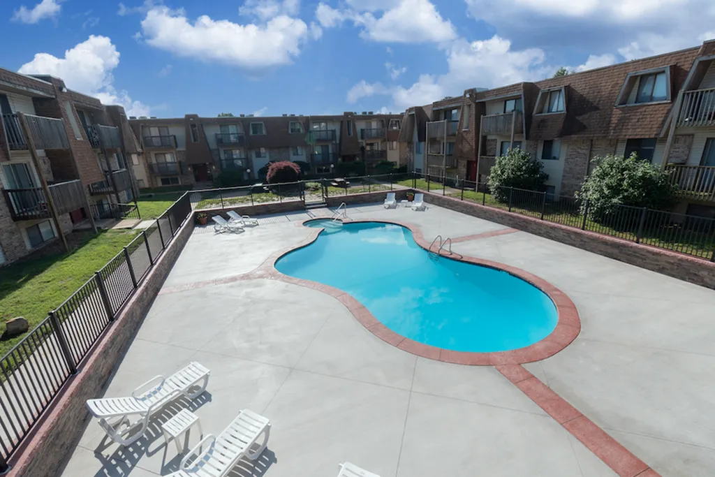 Large outdoor pool at Seminole Apartments in Springfield, MO, surrounded by lounge chairs and well-maintained landscaping.