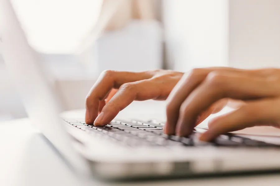 Focused hands typing on a laptop keyboard, symbolizing productivity and digital engagement.