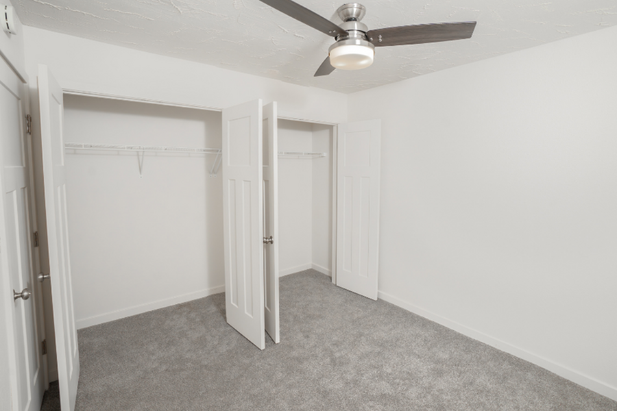 Bright, spacious bedroom with plush carpet, ceiling fan, and ample closet space.
