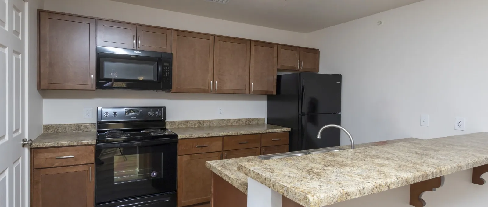 Classic kitchen layout with wood cabinets, black appliances, and matching countertops at Republic Palms Apartments.