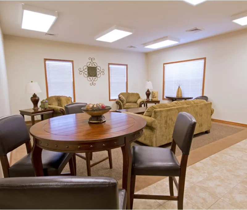 Clubhouse lounge at Republic Palms Apartments with casual seating including armchairs, a round table with chairs, and a cozy ambiance for resident gatherings.