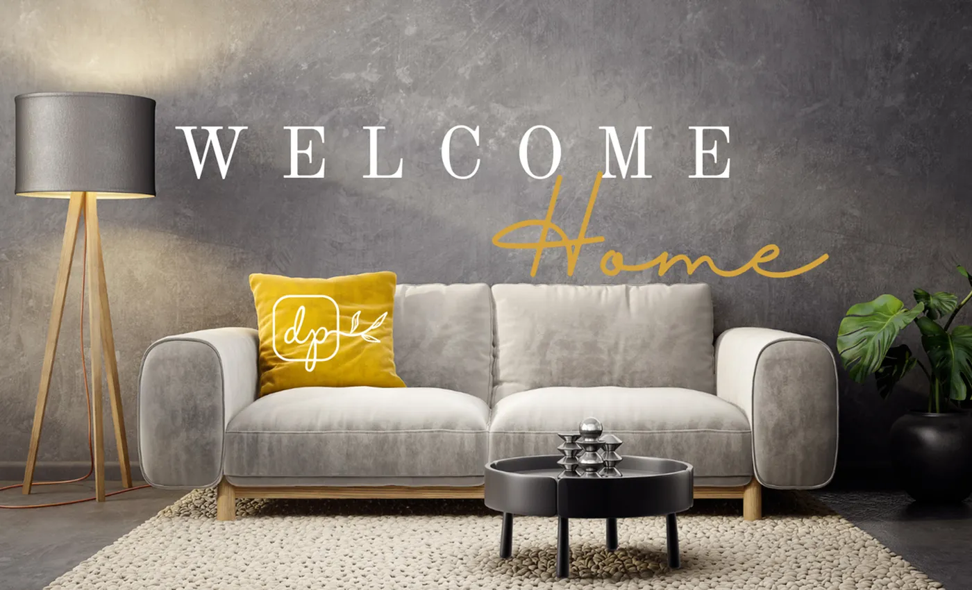 Modern living room with a gray velvet sofa, a yellow throw pillow featuring the 'dp' logo with a branch design, and the words 'WELCOME Home' on the wall behind&mdash;'WELCOME' in white uppercase serif font and