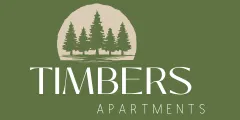 Logo for Timbers Apartments featuring stylized evergreen trees against a circular backdrop, with text on a green background.