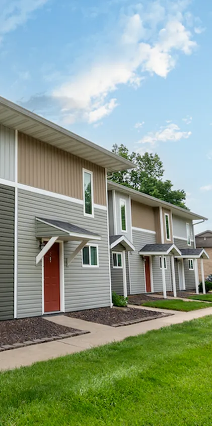 Close-up of updated townhome exteriors featuring neutral two-tone siding, red front doors, and individual covered entryways—designed for style and privacy in a Springfield rental community.