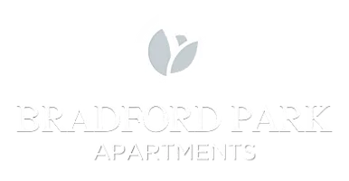 Bradford Park Apartments logo featuring a circular white emblem with a stylized light-gray tulip or leaf icon above the words &lsquo;Bradford Park&rsquo; in large white serif lettering and &lsquo;Apartments&rsquo; in smaller white text belo