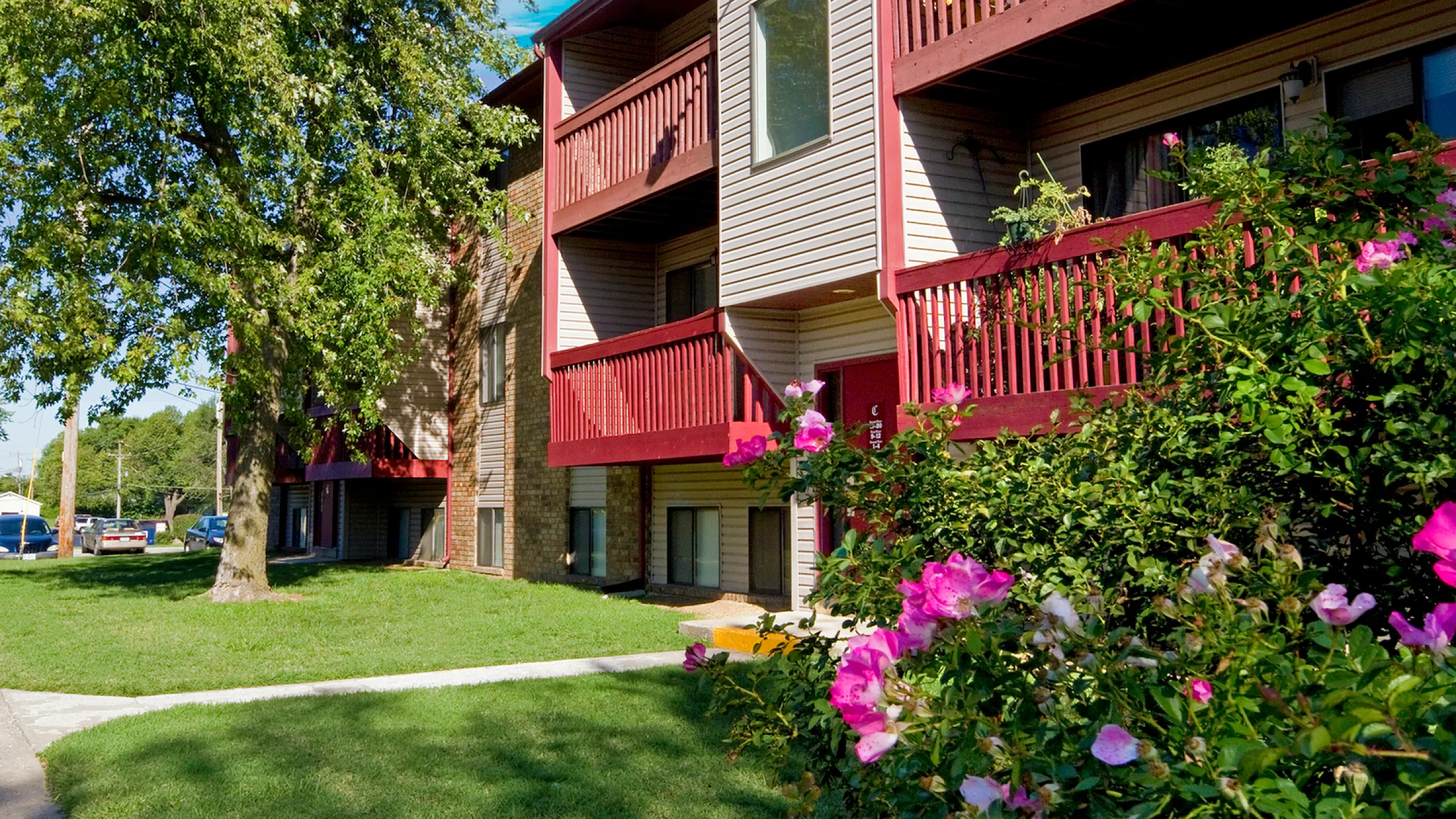 Charming apartment building with spacious balconies, vibrant garden, and lush green surroundings.
