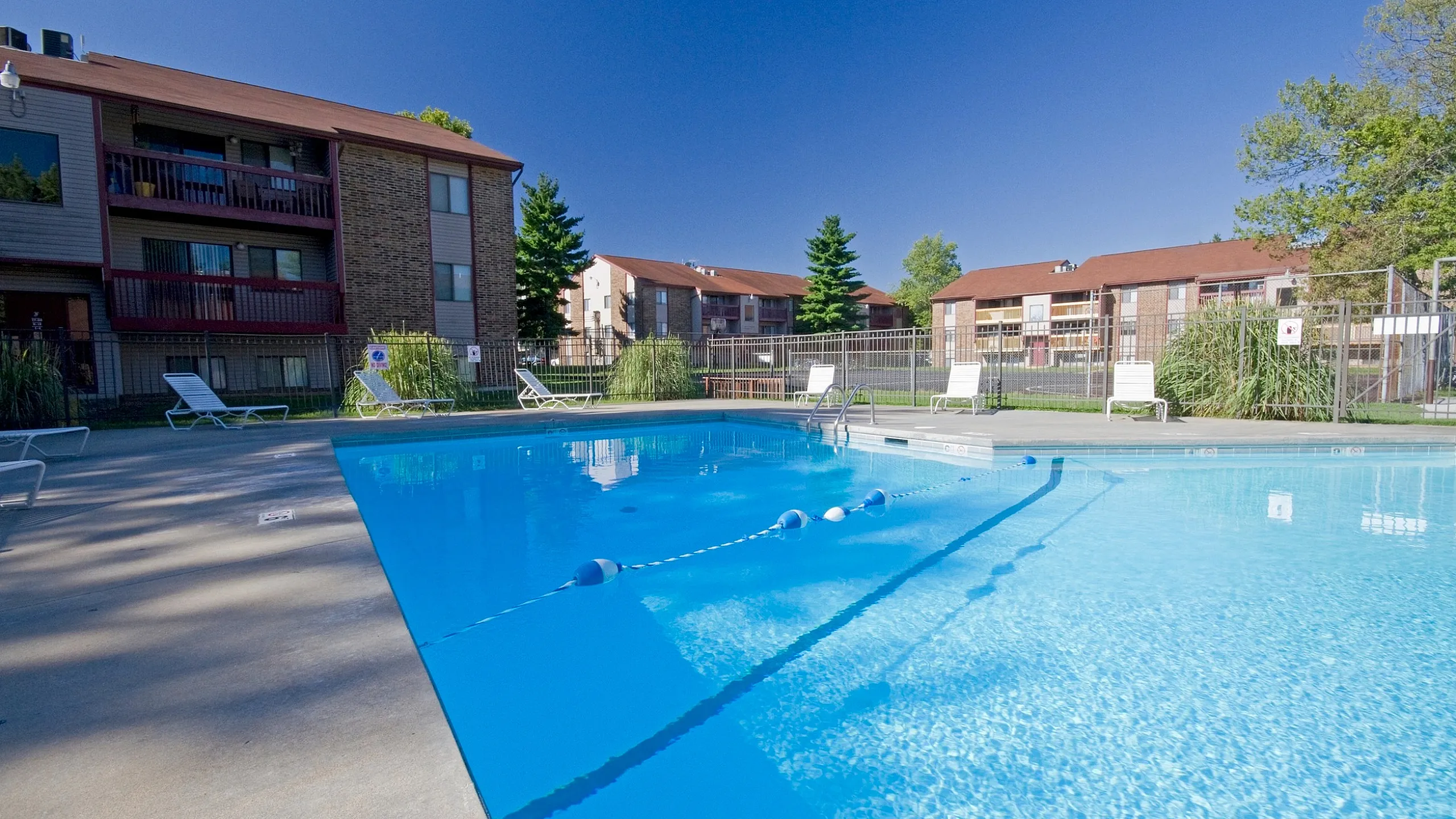 Inviting outdoor pool area with clear blue water, surrounded by well-maintained apartments, perfect for relaxing and enjoying sunny days.