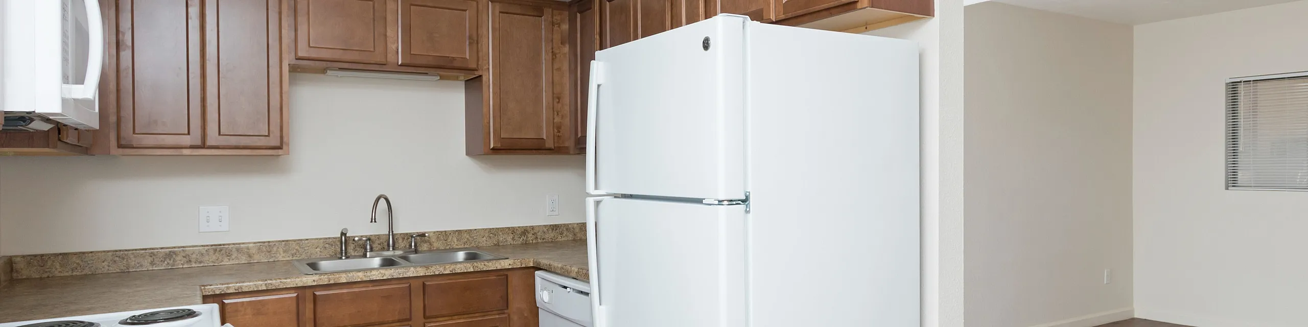 Modern kitchen with sleek wooden cabinetry, white appliances, and spacious open layout with hardwood floors.