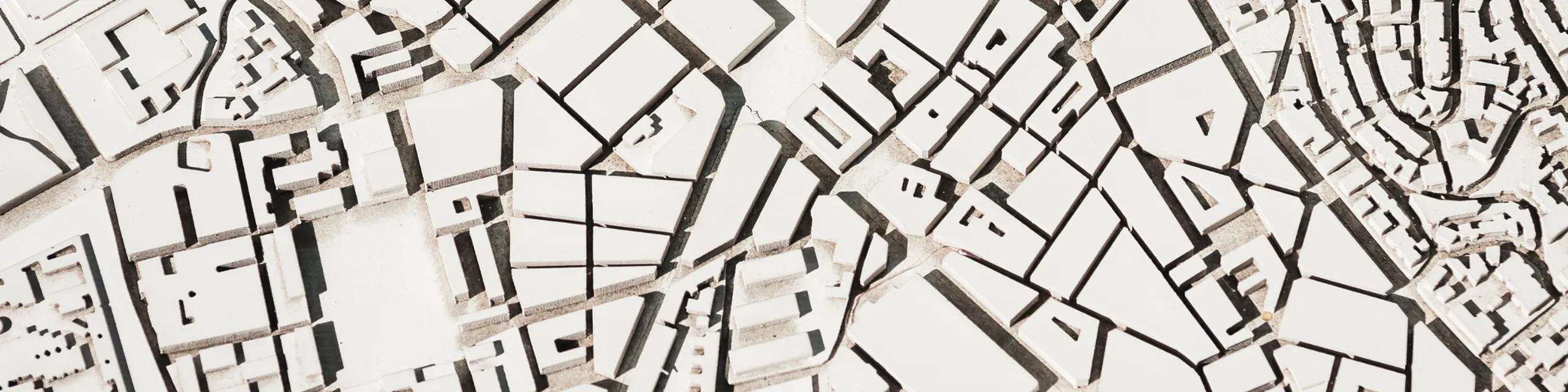 Intricate 3D city model featuring geometric white buildings with varied roof shapes, showcasing a detailed urban design.