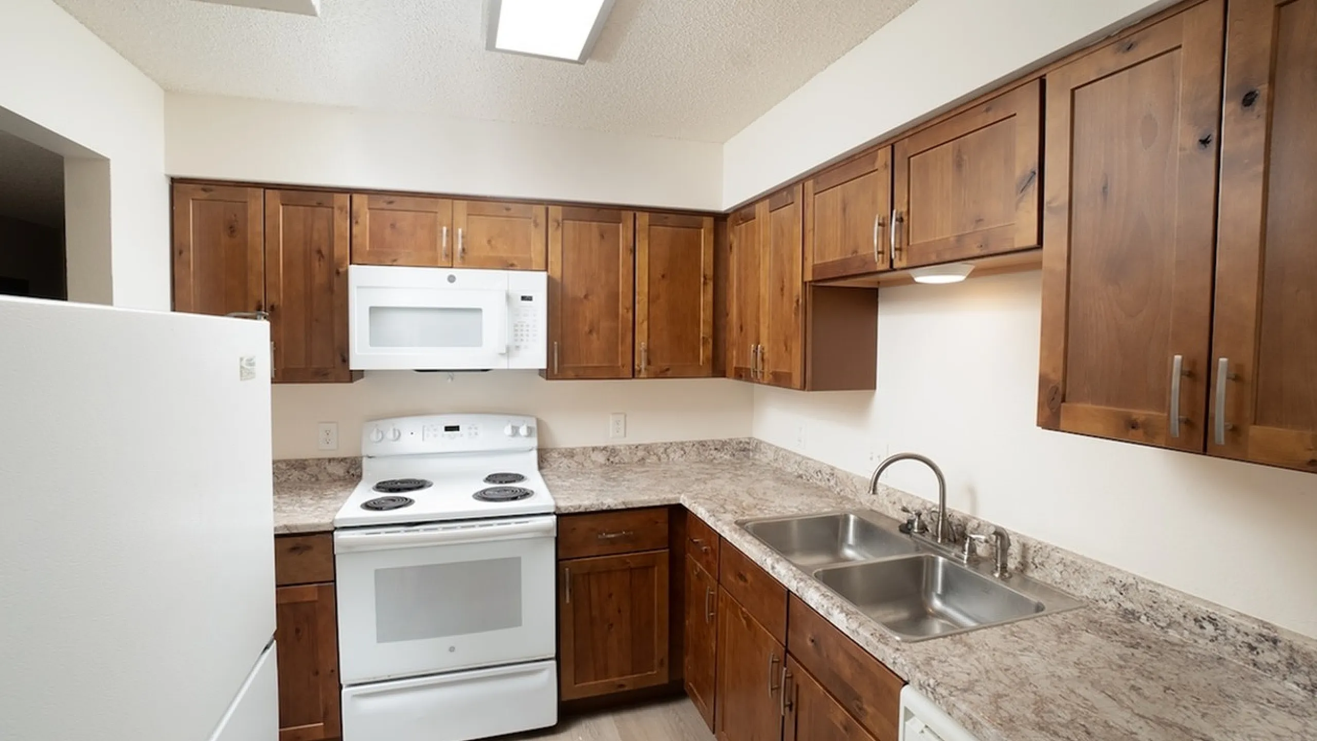 Charming kitchen with elegant wooden cabinetry, sleek marble countertops, and modern white appliances.