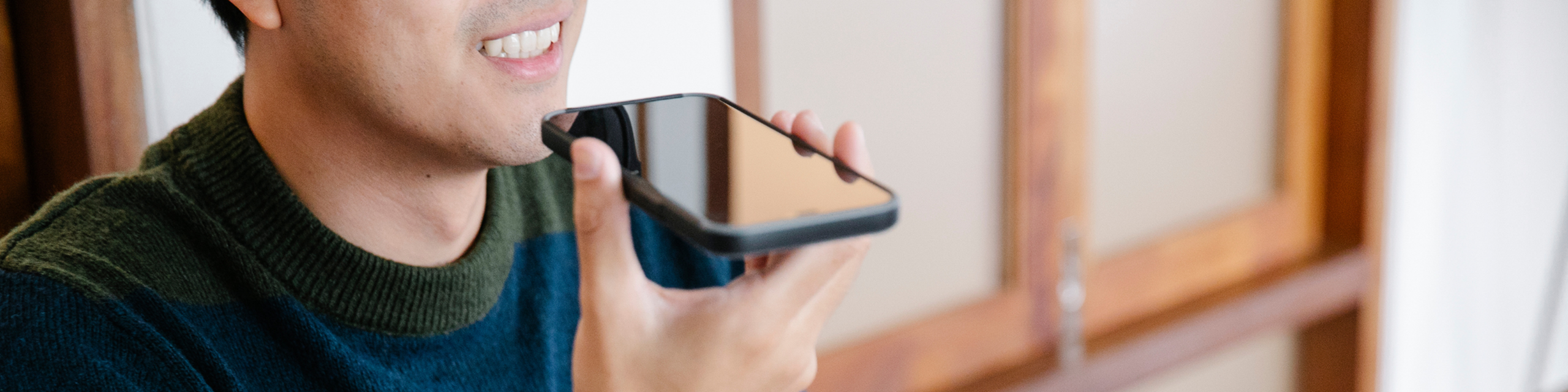 Person using a smartphone for a voice call or voice command in a relaxed indoor setting