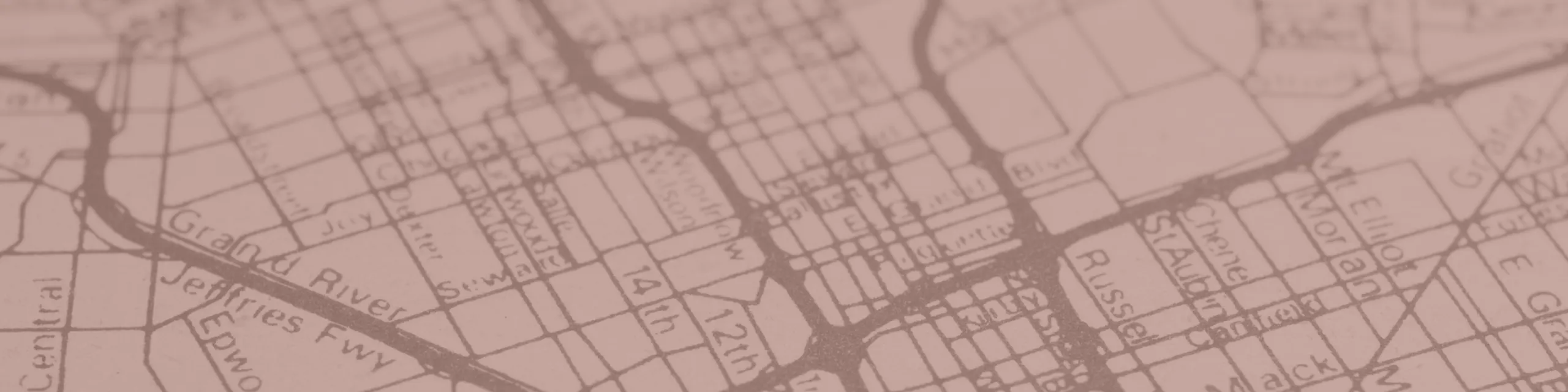 Vintage-style map featuring intricate street layout and neighborhoods, highlighted in a warm pink overlay.