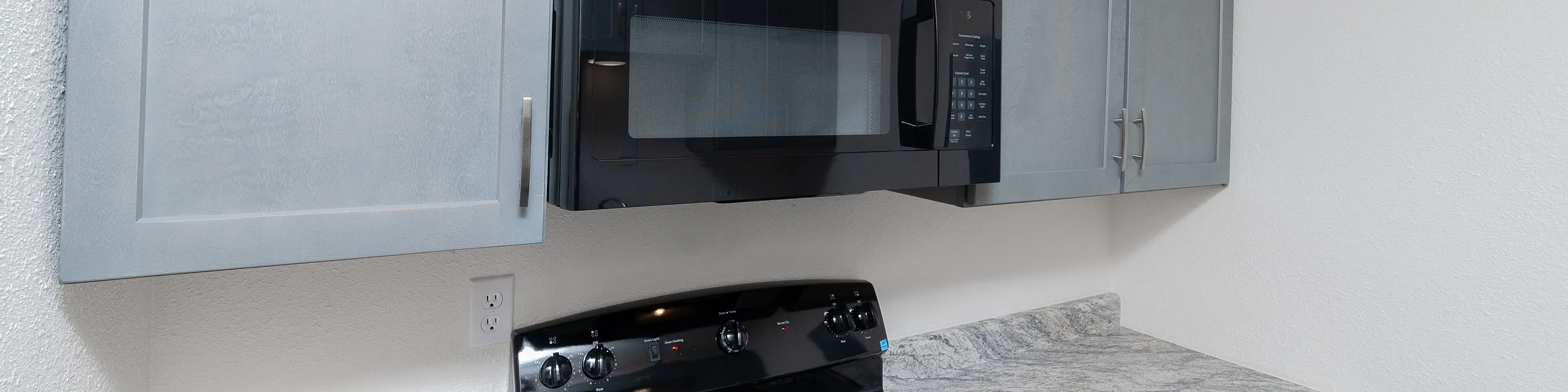 Modern kitchen with sleek black appliances, elegant gray cabinets, and stylish granite countertops.