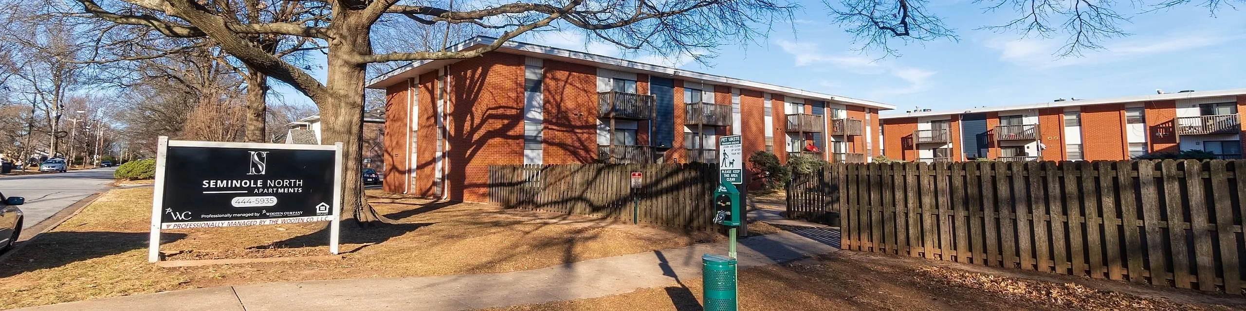 Inviting view of Seminole North Apartments highlighting brick exterior, vibrant landscaping, and spacious layout under a clear blue sky.