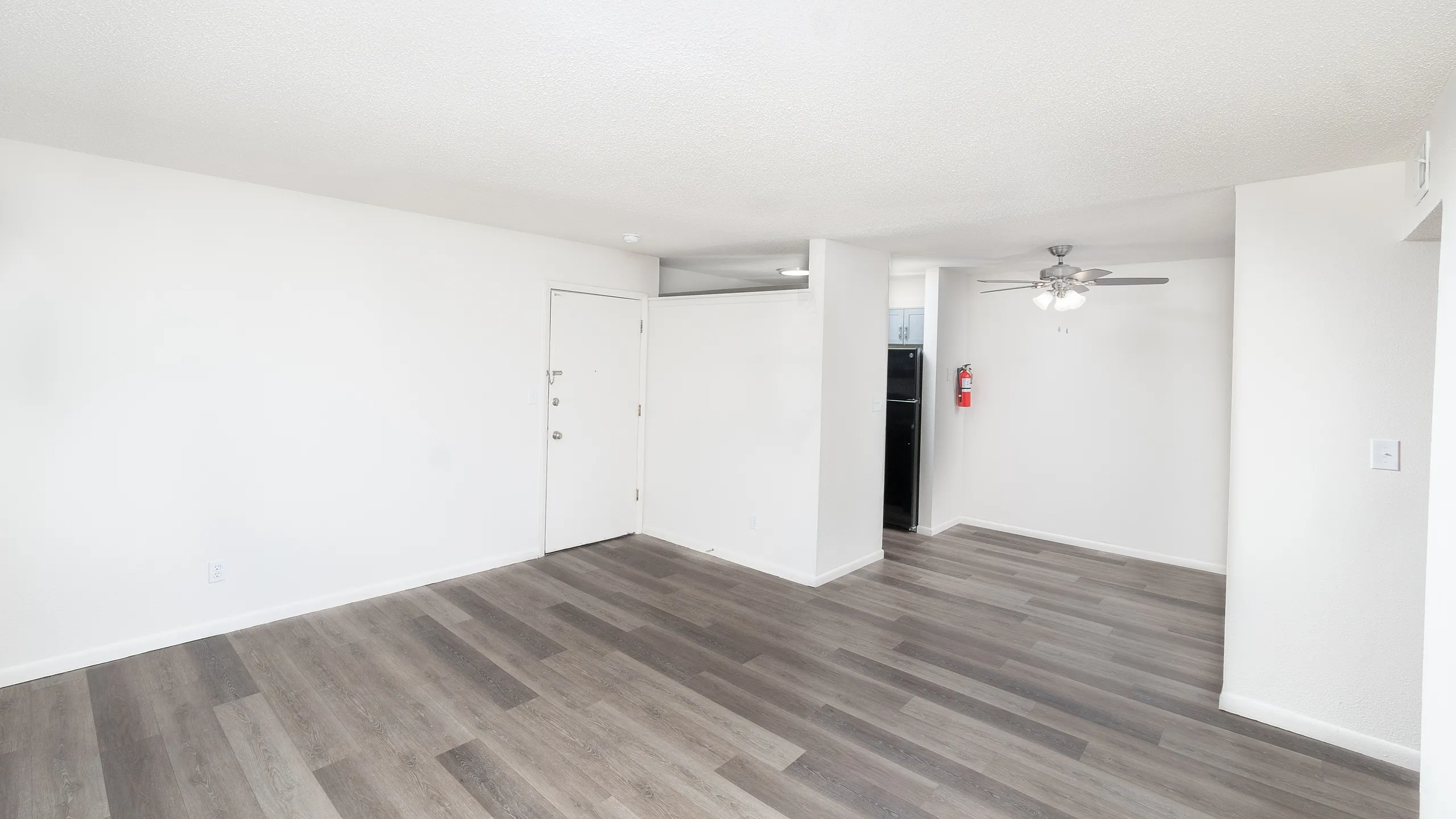 Bright and modern apartment interior with sleek wood flooring, ceiling fan, and a spacious open layout.
