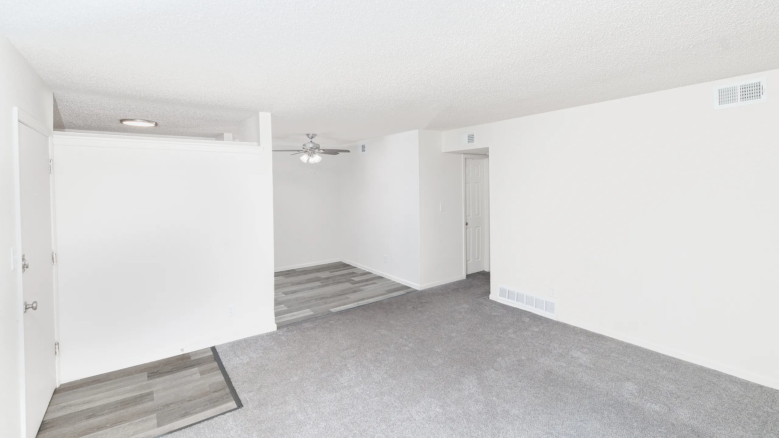 Bright and modern living space featuring fresh carpet, sleek laminate flooring, and an elegant ceiling fan, perfect for comfort and style.