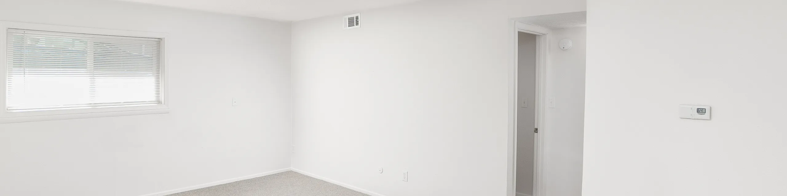 Bright and airy room with plush carpet, large window, and minimalist design, perfect for cozy living.