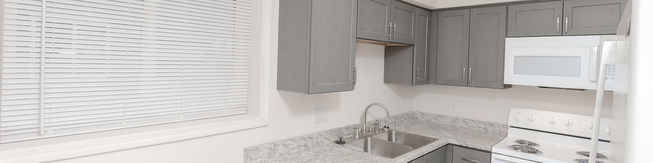 Bright and modern kitchen with sleek gray cabinets, marble countertops, and contemporary appliances.