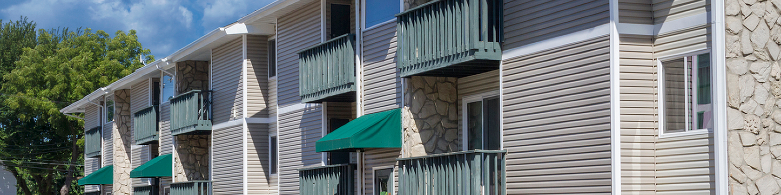 Charming apartment building with private balconies, vibrant landscaping, and convenient parking.