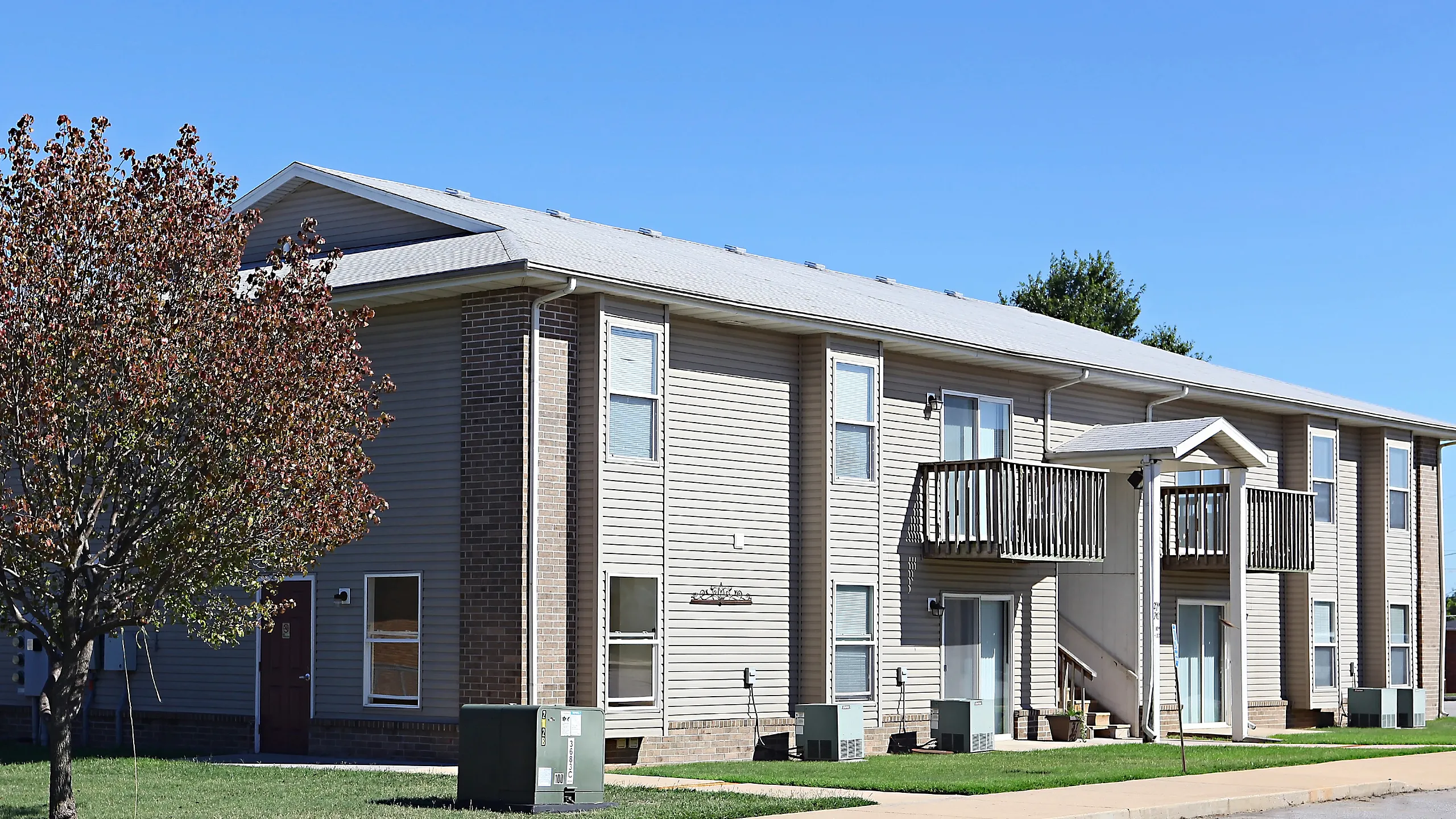 Charming two-story apartment building with balconies, nestled in a serene neighborhood and surrounded by lush greenery.