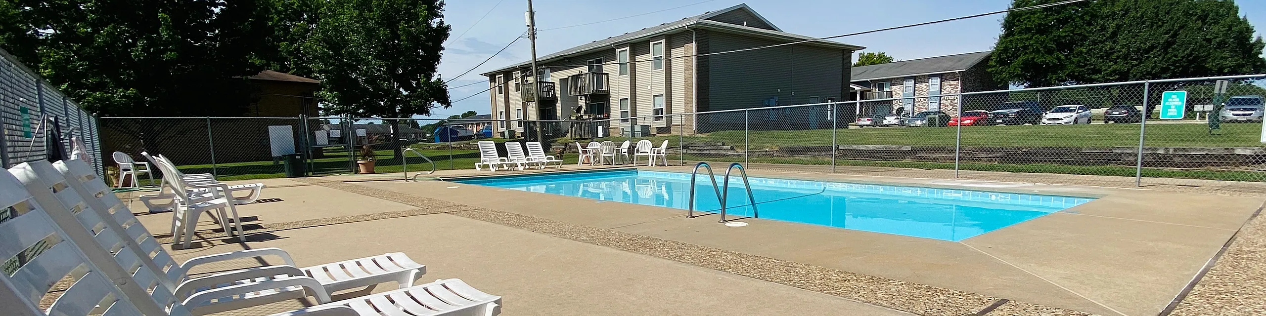 Inviting community pool area with ample sun loungers, perfect for relaxation amidst lush greenery.