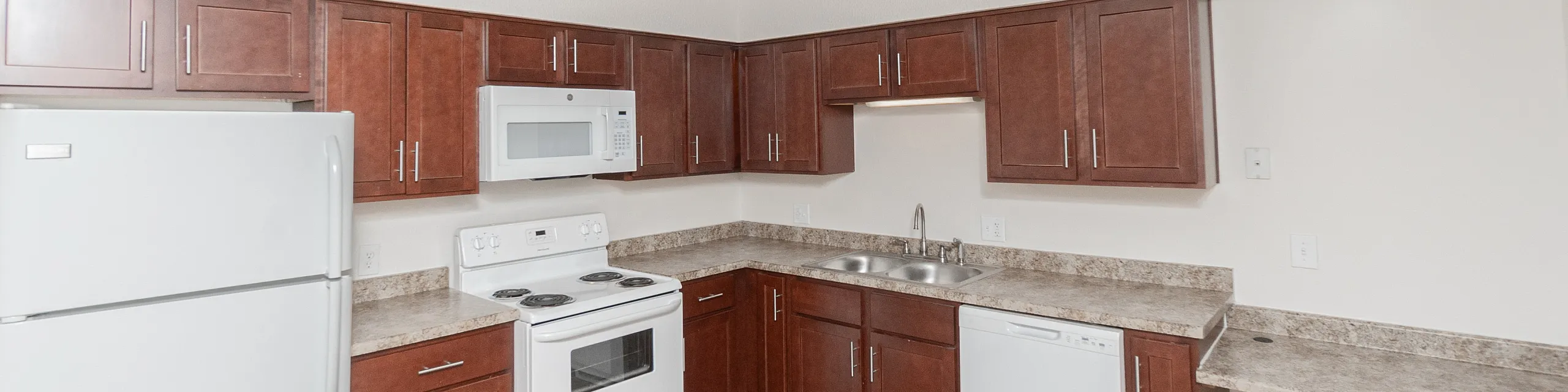 Modern kitchen with sleek dark wood cabinets, white appliances, and ample counter space, perfect for culinary creativity.