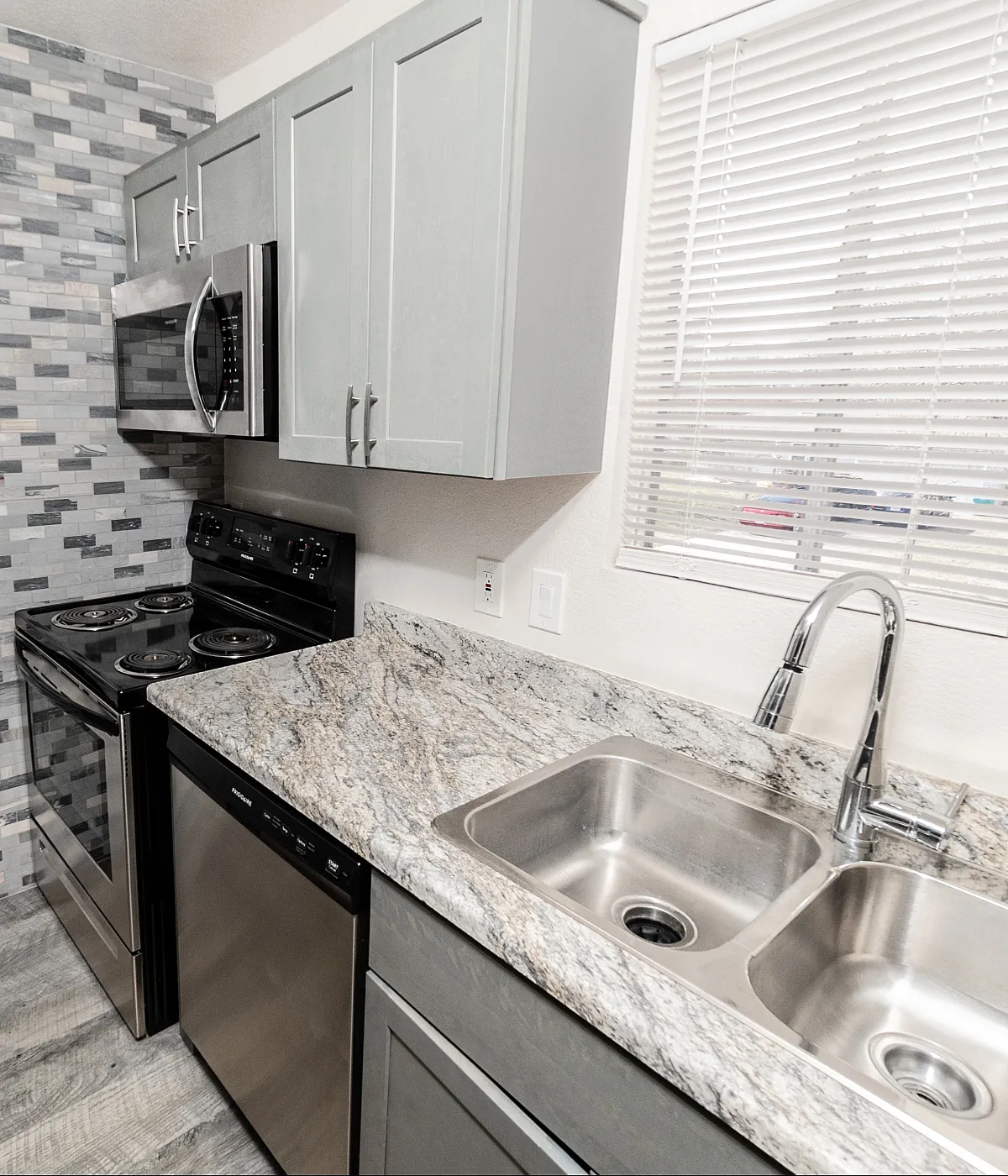 Contemporary kitchen with sleek stainless steel appliances, elegant granite countertops, and stylish mosaic tile backsplash.