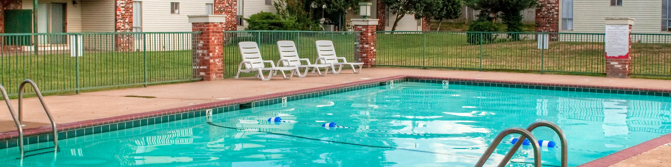 Inviting outdoor pool with comfortable lounge chairs in a charming apartment complex setting, exuding relaxation and leisure.