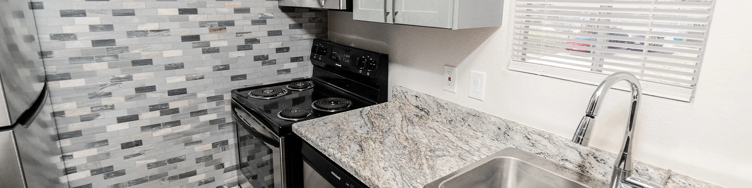 Modern kitchen with sleek stainless steel appliances, dual sink, granite countertops, and stylish tile backsplash.