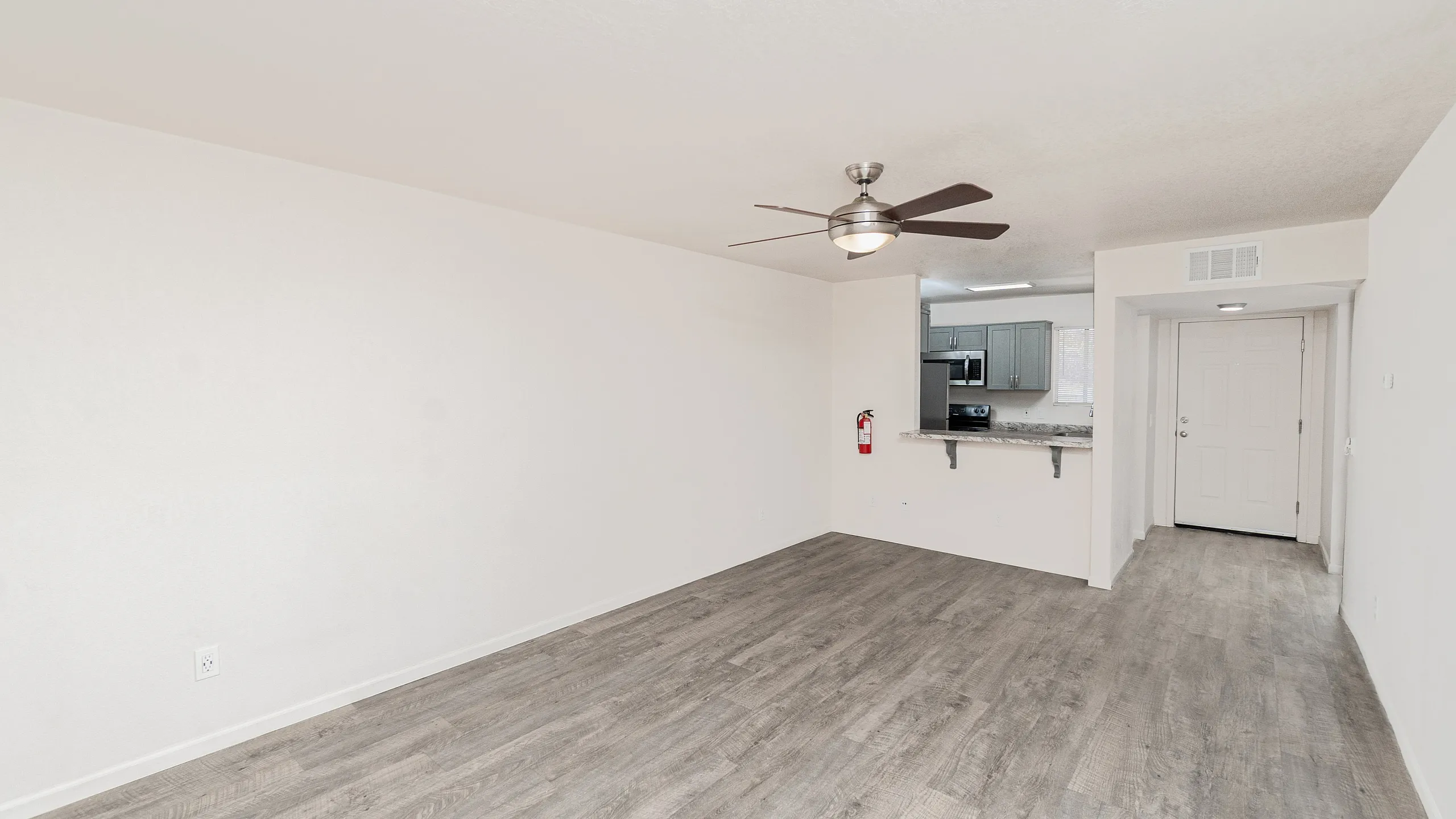 Bright, open-concept living space with modern ceiling fan and sleek hardwood floors, adjacent to a stylish kitchen with stainless steel appliances.
