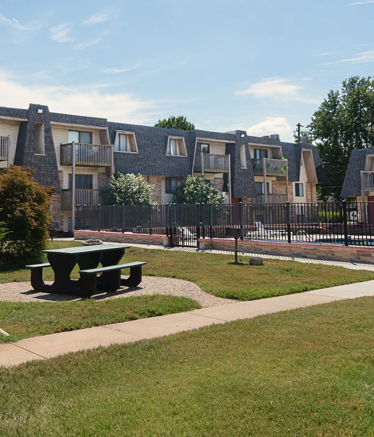 Bright and inviting apartment complex with spacious balconies overlooking a well-maintained garden and a sparkling swimming pool.