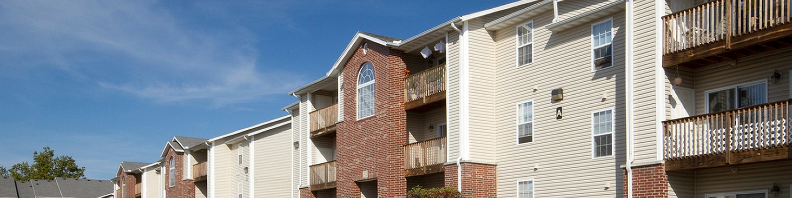 Inviting apartment complex with charming balconies and ample parking under a clear blue sky.